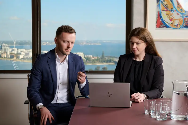 Two O'Sullivan Davies lawyers meeting at a desk with a laptop